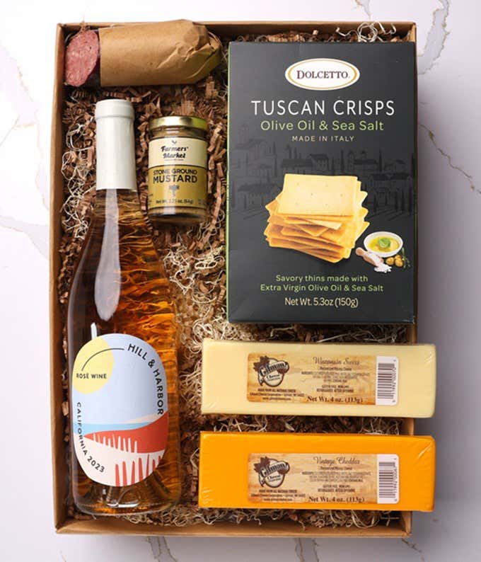 A gift box with a bottle of California Rosé Wine, two types of cheese, crackers, stone-ground mustard, and a summer sausage.