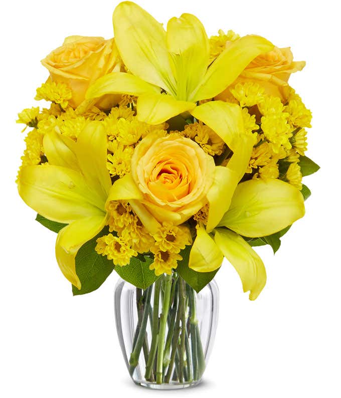 A bouquet featuring yellow lilies, yellow roses, and yellow poms, with an optional glass vase.