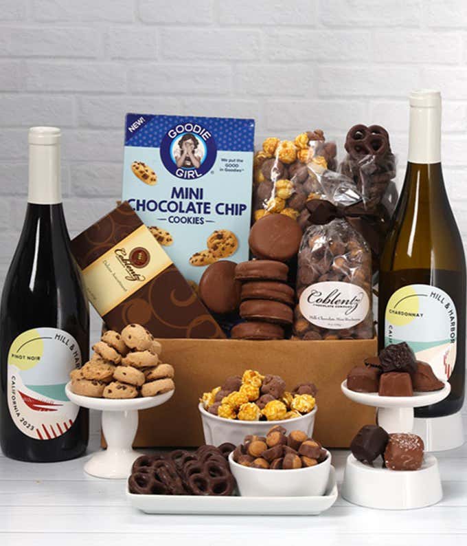 A gift set with 2 bottles of wine - red and white, paired with chocolate pretzels, caramel popcorn, mini cookies, chocolate peanut butter buckeyes, six chocolate-covered Oreos, and a box assorted chocolates.