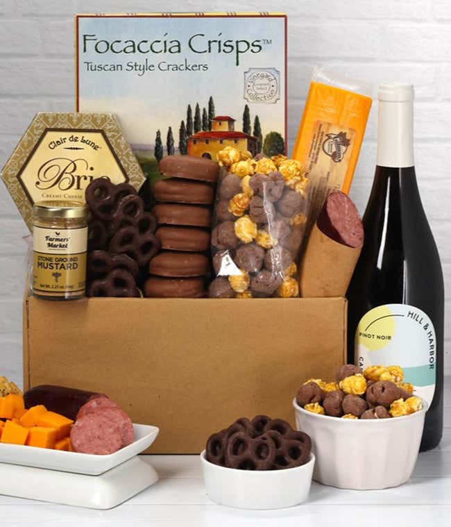 A gift set featuring a bottle of California Pinot Noir, focaccia crisps, 2 cheeses, mustard, summer sausage, caramel popcorn, chocolate pretzels, and 6 chocolate-covered Oreos for a sweet and savory gourmet experience.
